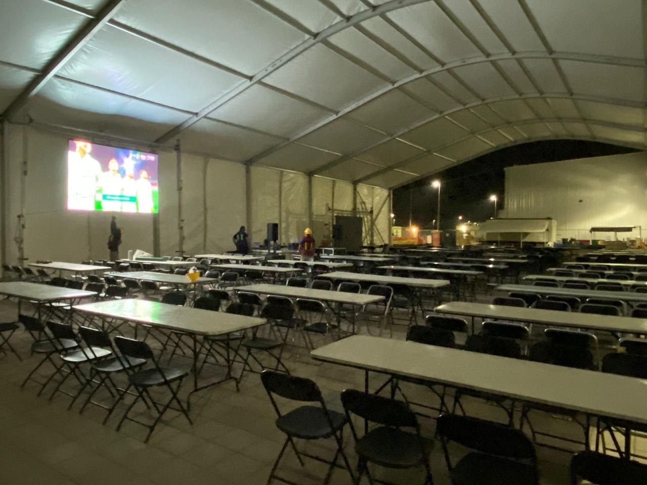 Carpa de evento iluminada con pantalla y montaje de mesas